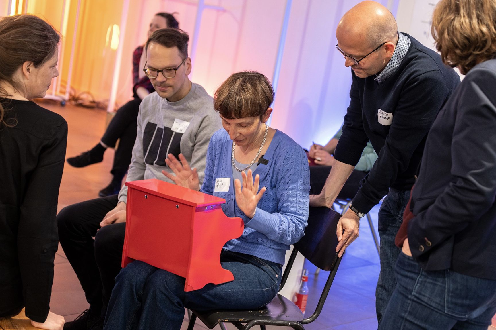 A group of people gathering around Prof. Ariane Jeßulat while she illustrates her point on a small modell of a piano